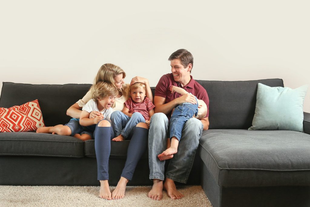 Young family with three boys lifestyle at home on the couch playing together